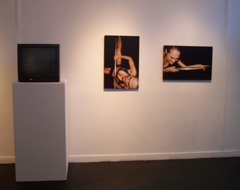 installation view of still photos next to tv playing video
